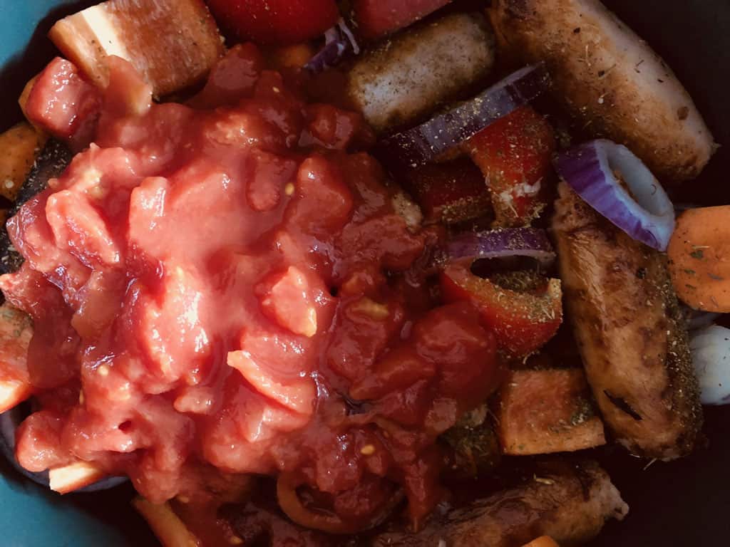 adding chopped tomatoes to sausage casserole