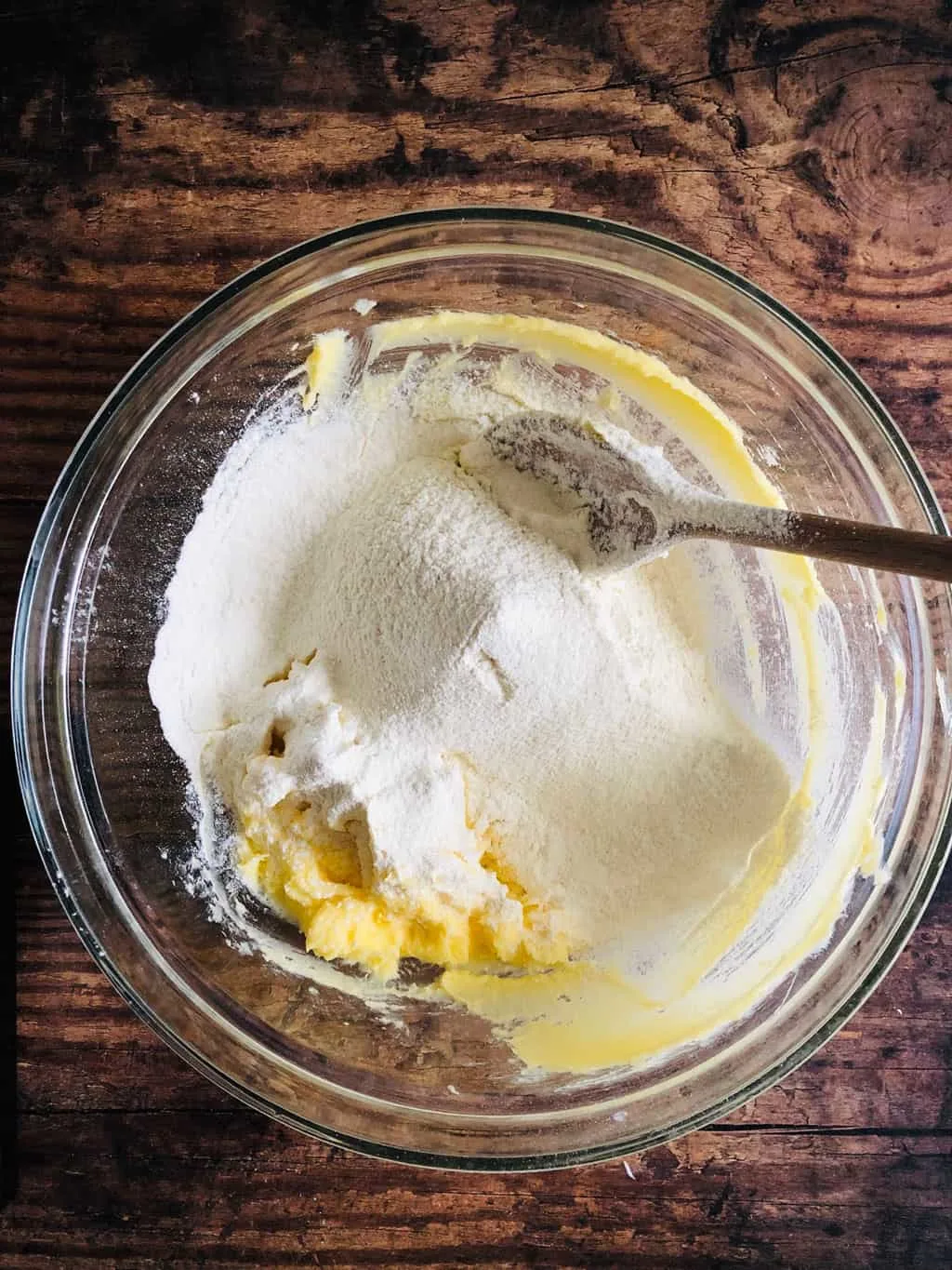 sugar, butter and flour in a mixing bowl with a wooden spoon