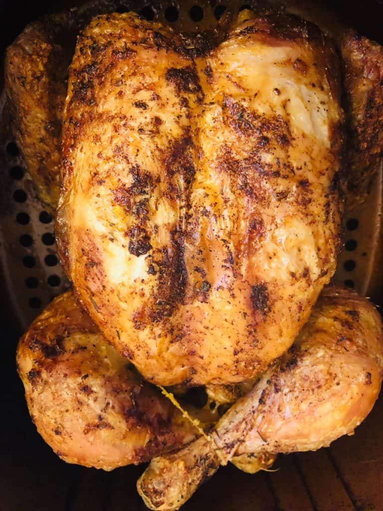 cooked whole chicken in an air fryer basket