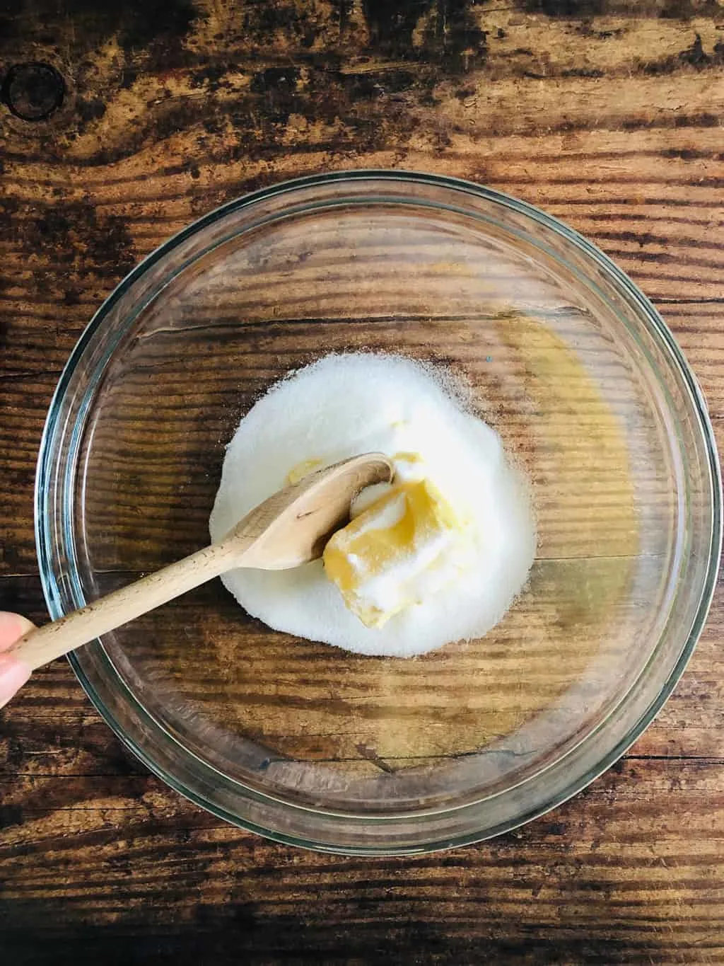 butter and suagr in mixing bowl with wooden spoon