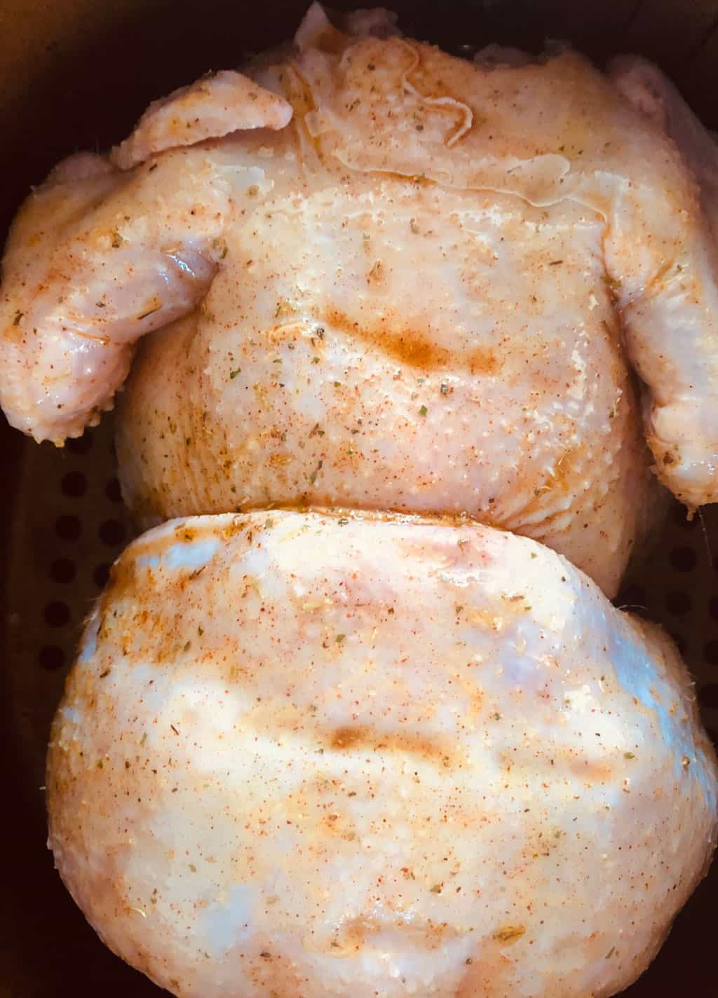 whole chicken in air fryer bresat side down in an air fryer basket