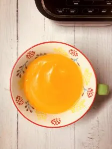 carrot and lentil soup in a bowl next to Ninja soup maker