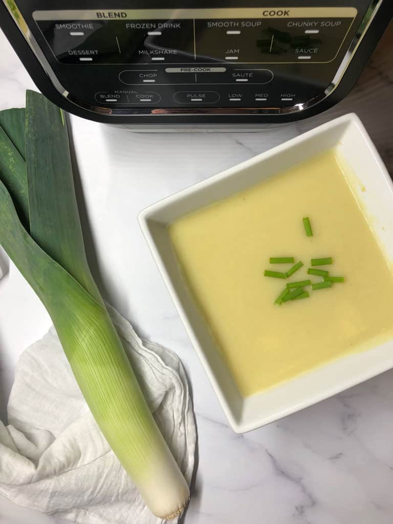 leek and potato soup with a raw leek next to the ninja blender and soup maker