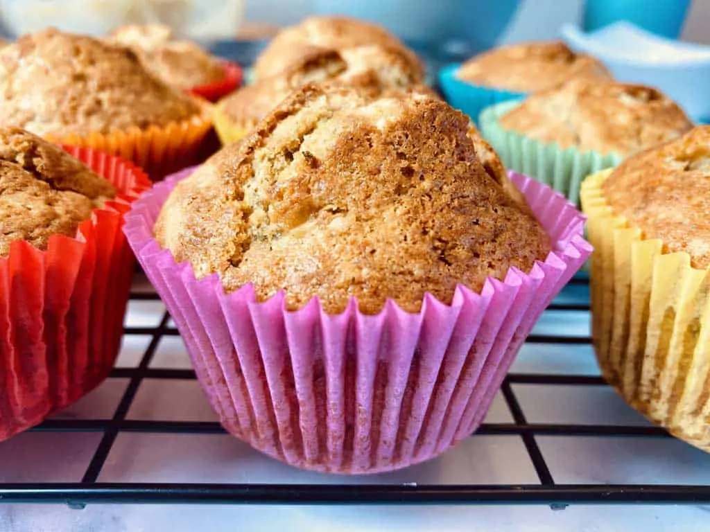 close up of banana muffin in pink case among other muffins