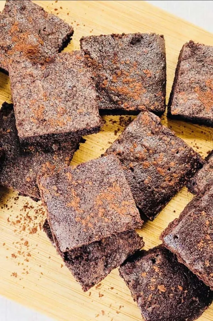 chopped up brownies on a chopping board with cocoa powder sprinkled on top