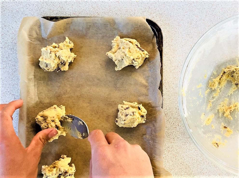 adding cookie dough to baking tray