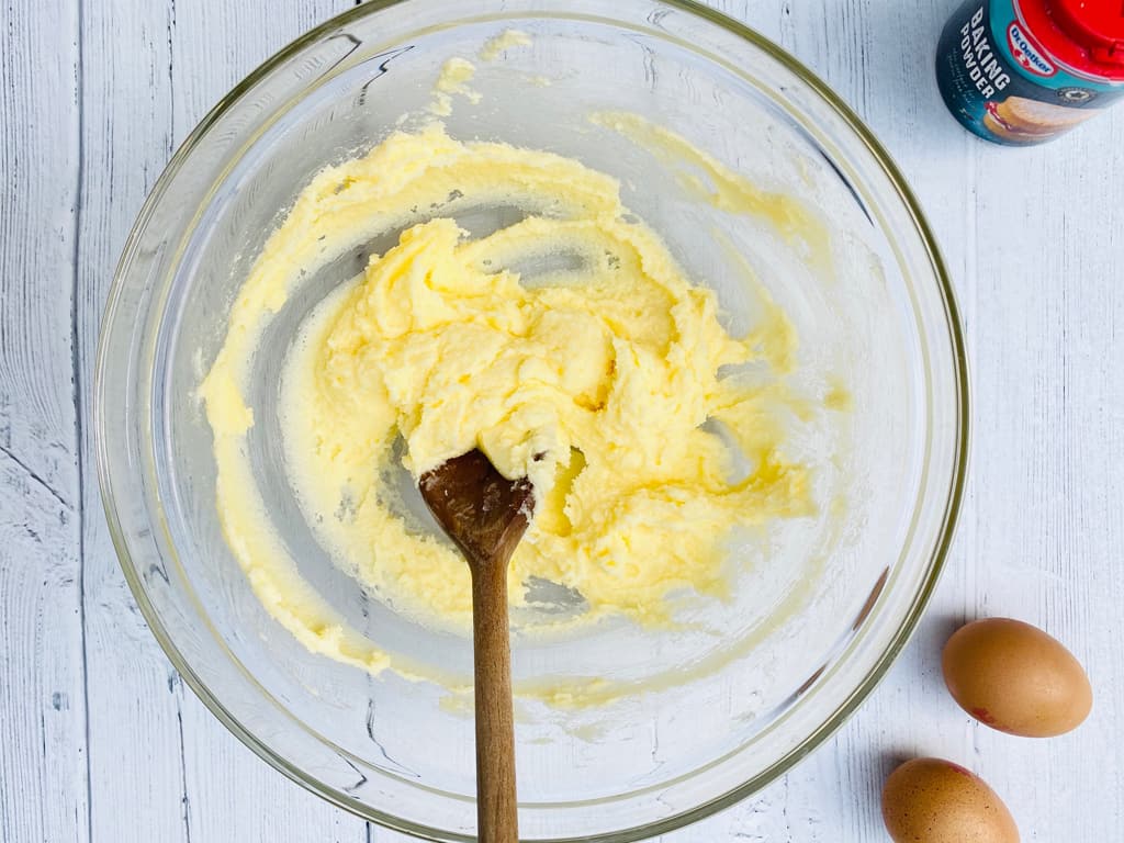 butter and sugar creamed in a bowl with wooden spoon