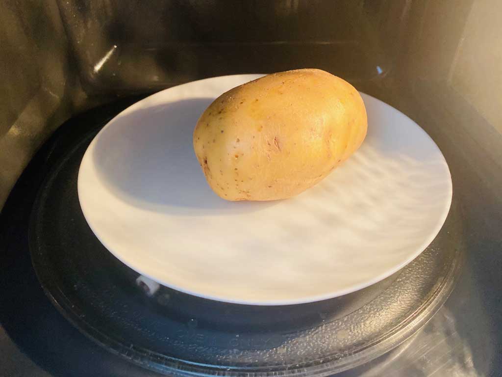 potato on plate in microwave ready to cook