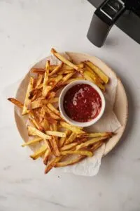 air fried chips on plate with tomato ketchup in a pot next to an air fryer