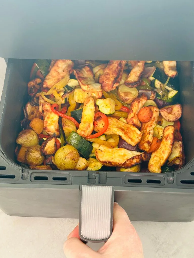 halloumi slices, peppers, courgetts, potatoes butternut squash in an air fryer basket pulled out to show it