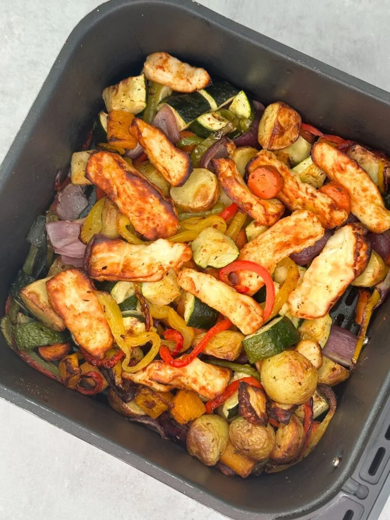 halloumi, courgettes, red onion, new potatoes, red, green and yellow peppers, butternut squash, carrots. All air fried and ready to eat in an overhead shot of the air fryer basket