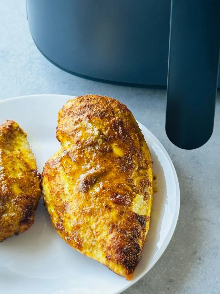 air fried chicken breasts with a Moroccan inspired marinade next to an air fryer