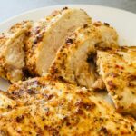 sliced piri piri chicken breast on a white plate next to an air fryer