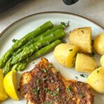 Cajun cod with new potatoes, lemon, asparagus next to air fryer
