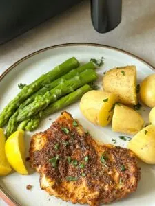 Cajun cod with new potatoes, lemon, asparagus next to air fryer