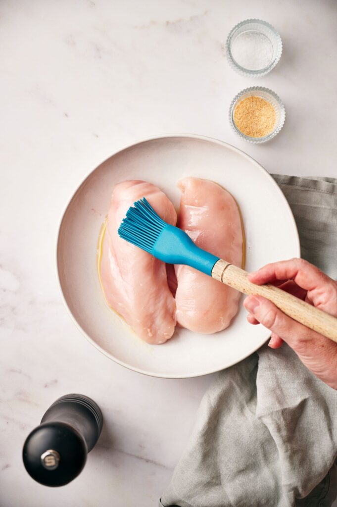 Brushing oil on chicken breasts for air fryer