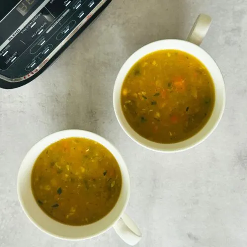 Chunky Vegetable Soup in two soup mugs next to a Ninja soup maker