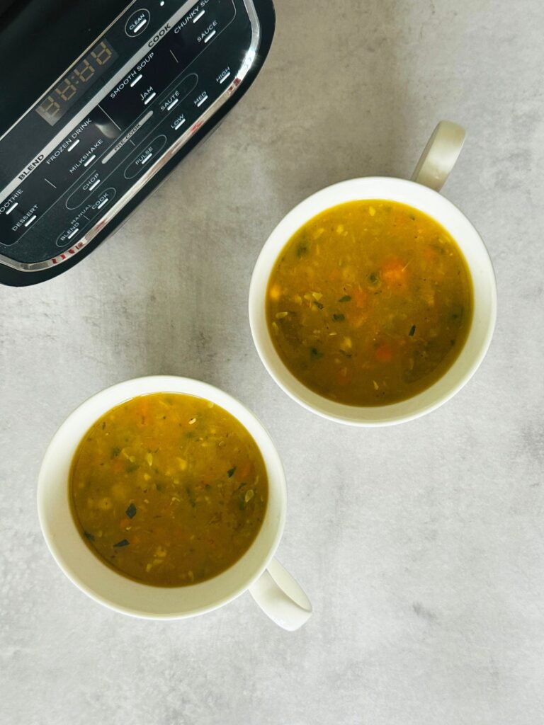 Chunky Vegetable Soup in two soup mugs next to a Ninja soup maker