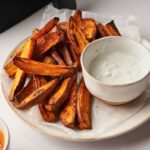 sweet potato wedges on a plate next to a dip and air fryer