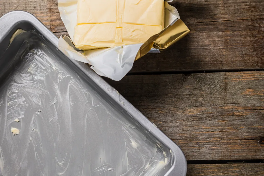 greasing baking tin with butter