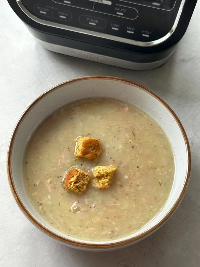 ham and potato soup in a bowl with croutons in front of a Ninja soup maker
