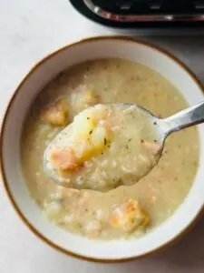 ham and potato soup on a spoon above the rest of the soup in a bowl