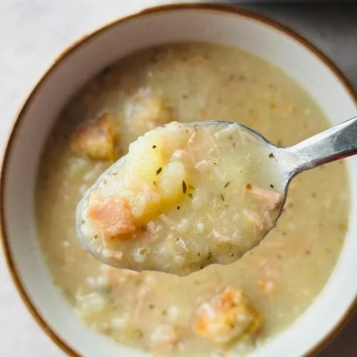 ham and potato soup on a spoon above the rest of the soup in a bowl