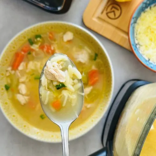 Lemon chicken and orzo soup in a soup maker and bowl with a spoon holding some of it