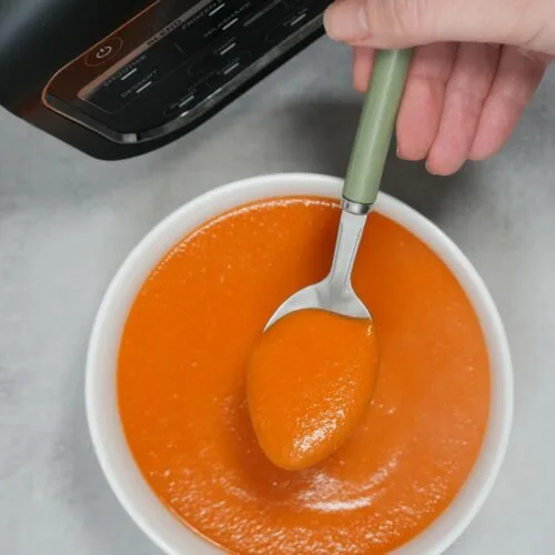 tomato red lentil and chickpea soup in a bowl with a spoon