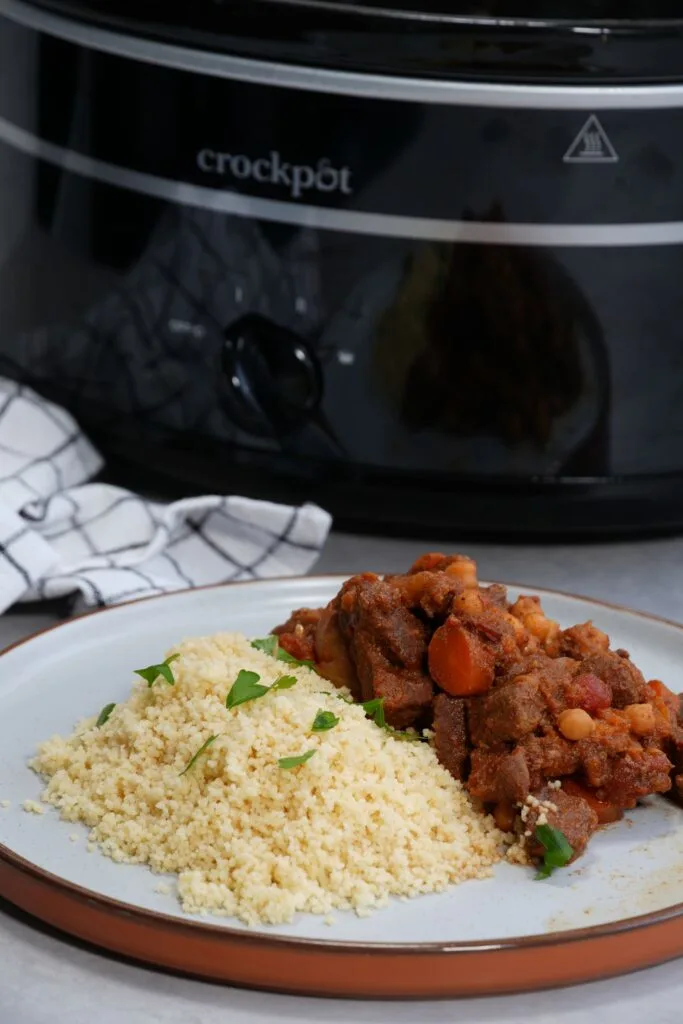 Moroccan style beef stew next to some cous cous in front of a slow cooker