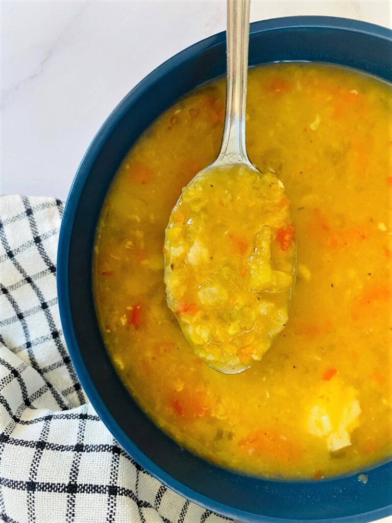 Mulligatawny soup in a blue bowl with a spoon dipped in