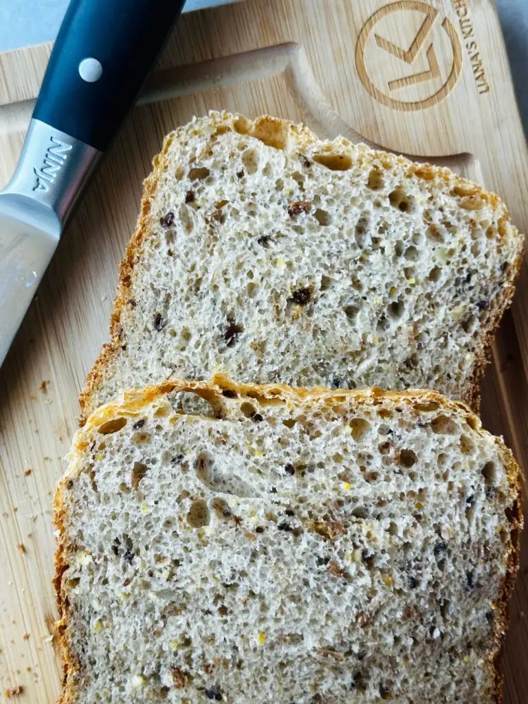 multigrain bread loaf sliced on a Liana's Kitchen wooden chopping board with a Ninja Kitchen knife next to it