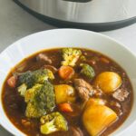 beef stew in a white bowl in front of a Ninja Foodi 15 in 1