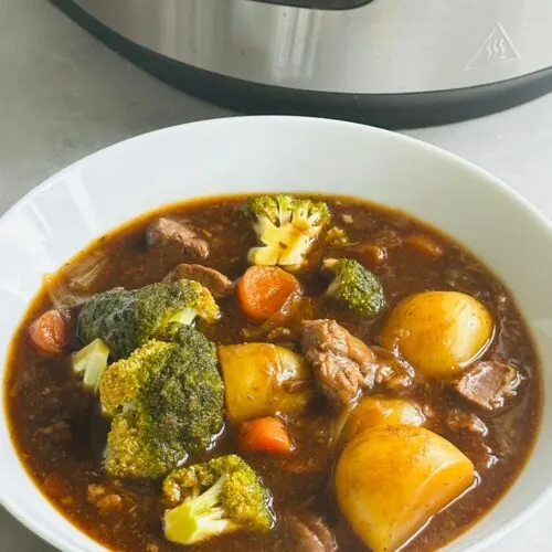 beef stew in a white bowl in front of a Ninja Foodi 15 in 1
