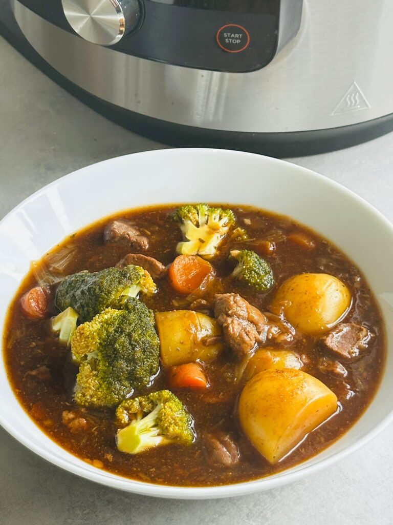 beef stew in a white bowl in front of a Ninja Foodi 15 in 1 