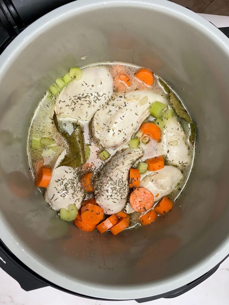 chicken breasts, herbs, carrots, stock and celery in Ninja Foodi pot