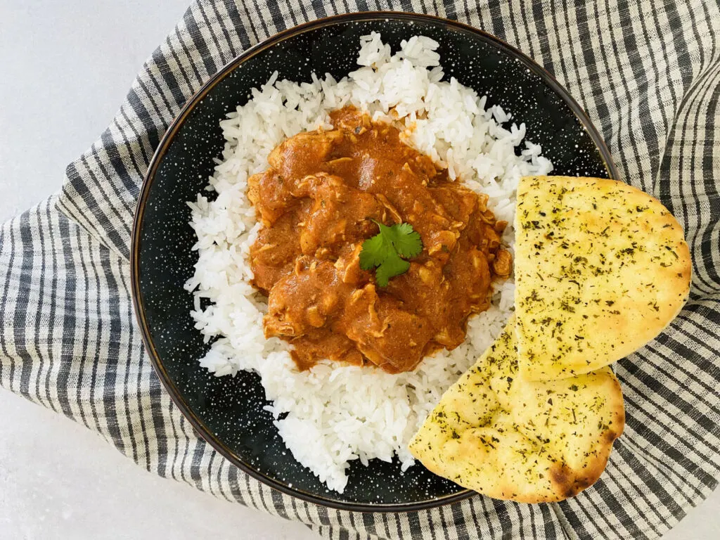 Chicken curry made in the Ninja Foodi served on a plate with white rice and naan bread.