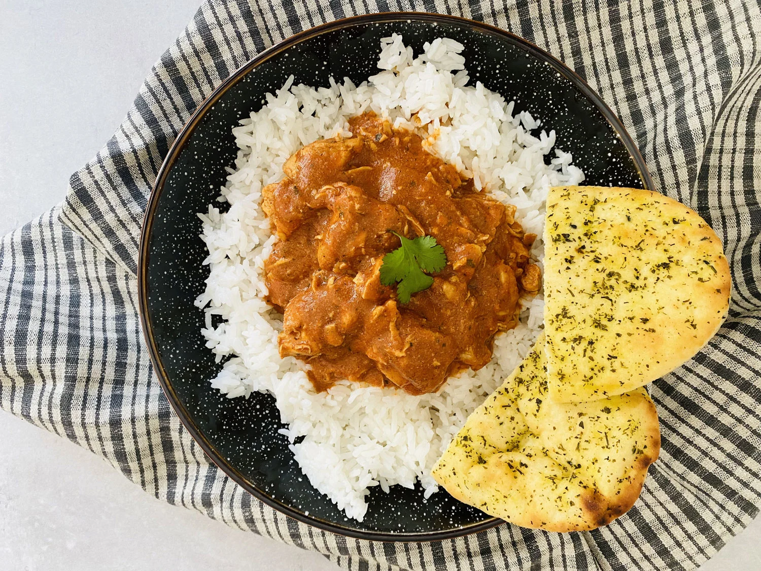 Chicken curry on a plate with white rice and naan bread