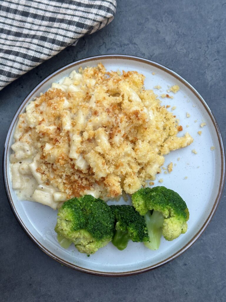 macaroni cheese on plate with two florets of broccoli