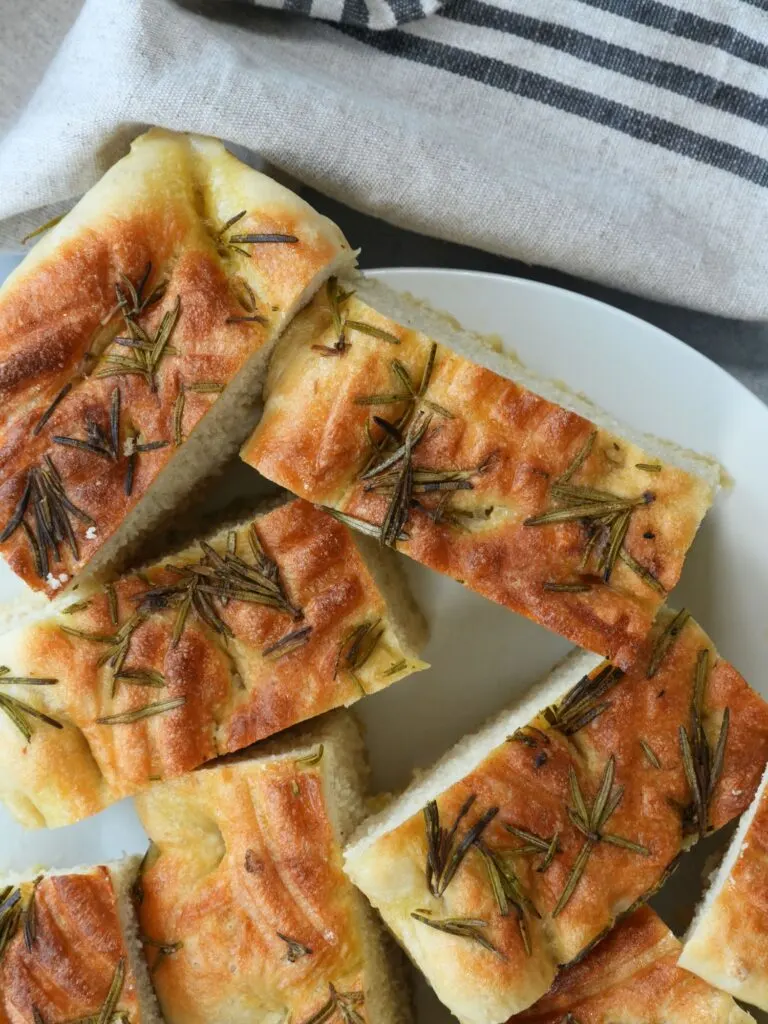 freshly baked focaccia sliced  with fresh rosemary on top 