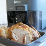 whole roast chicken in a serving bowl, carved, in front of a Ninja