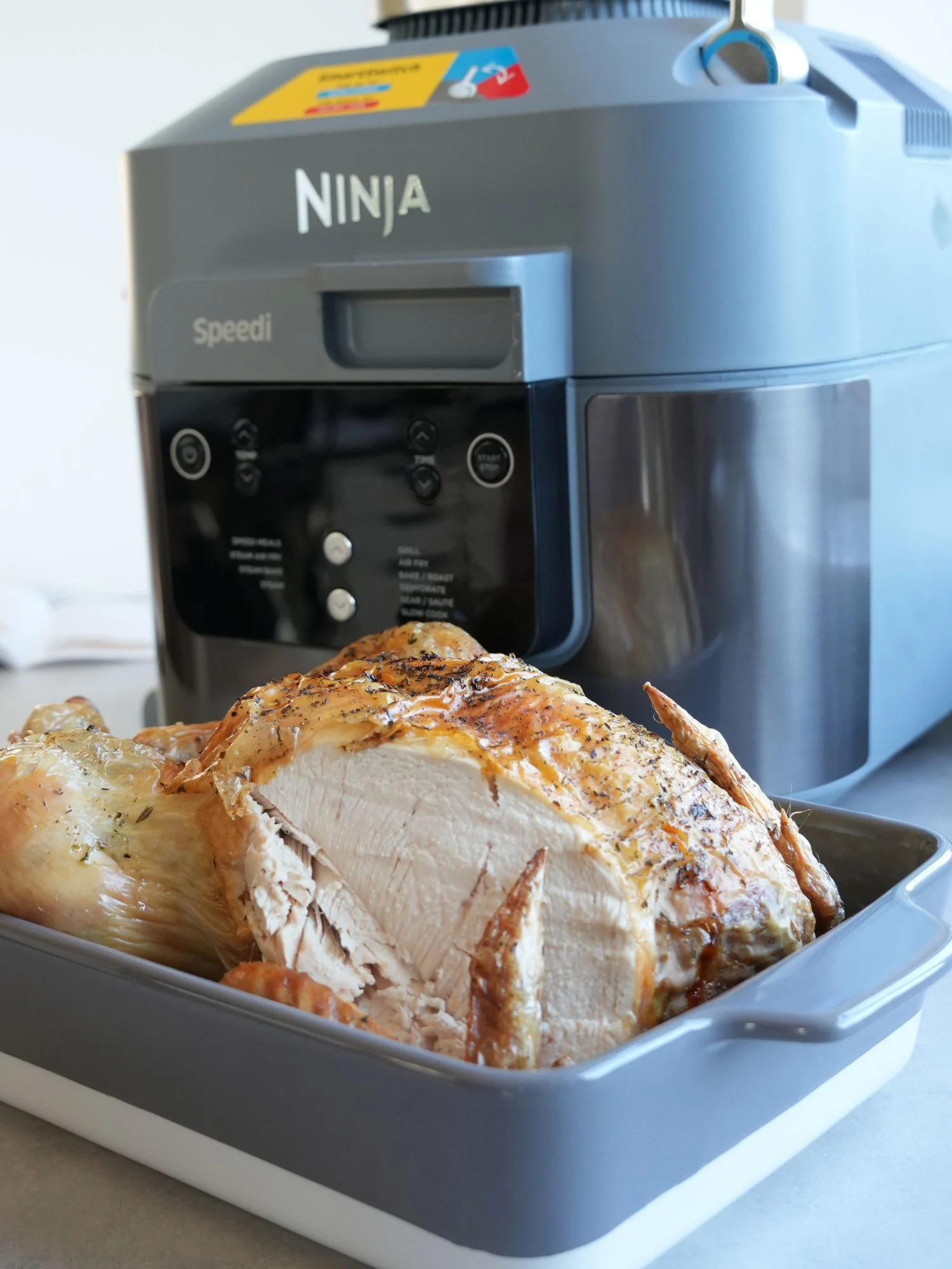 whole roast chicken in a serving bowl, carved, in front of a Ninja