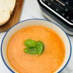tomato and basil soup in a bowl next to a Ninja soup maker