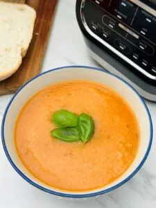 tomato and basil soup in a bowl next to a Ninja soup maker
