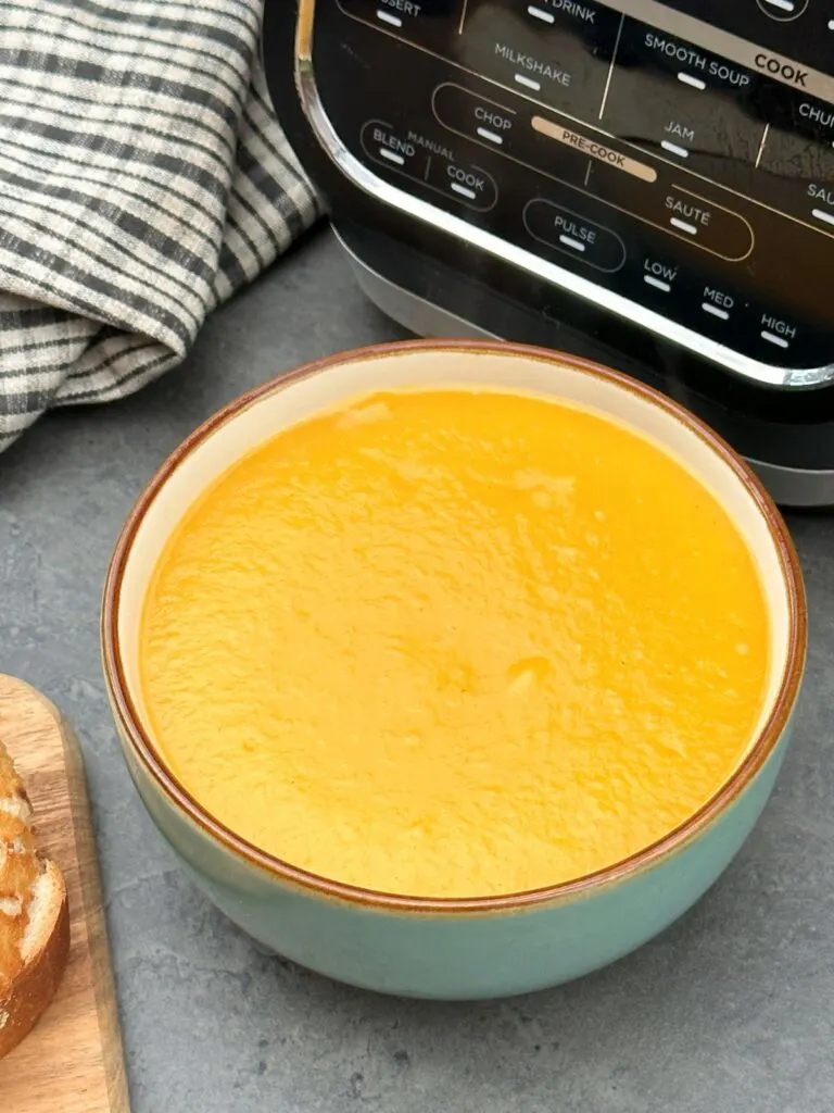 vegetable soup in a bowl next to a Ninja soup maker