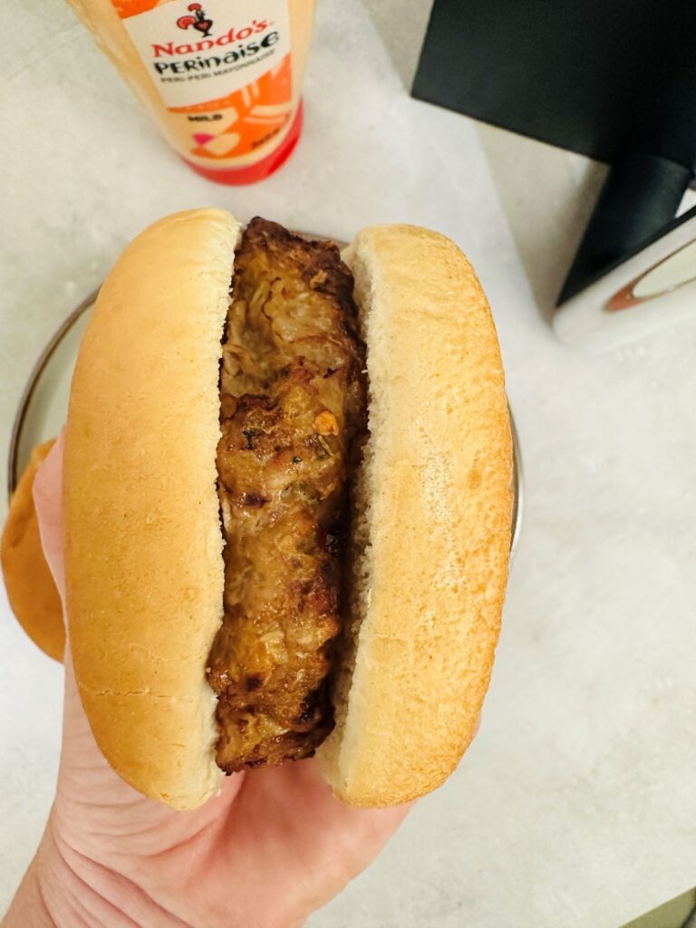 piri piri pork burger in a bun above Nandos Perinaise sauce next to an air fryer