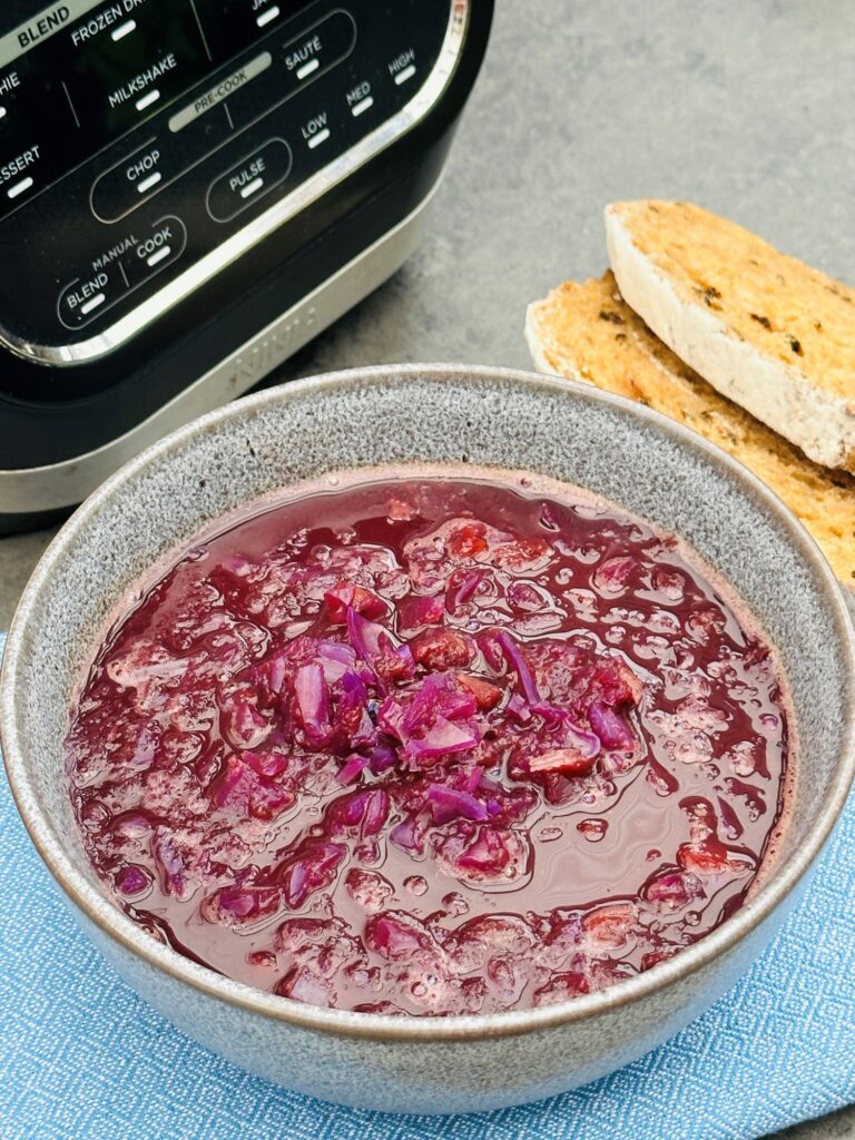 red cabbage soup next to slices of bread and a Ninja soup maker