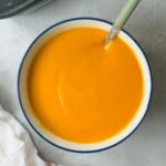 roasted tomato and garlic soup in a bowl with a spoon in it next to a white teatowel and a ninja soup maker
