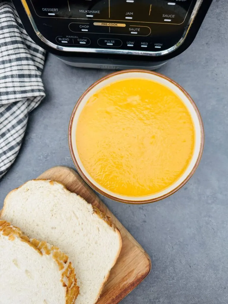 vegetable soup next to slices of bread and Ninja soup maker