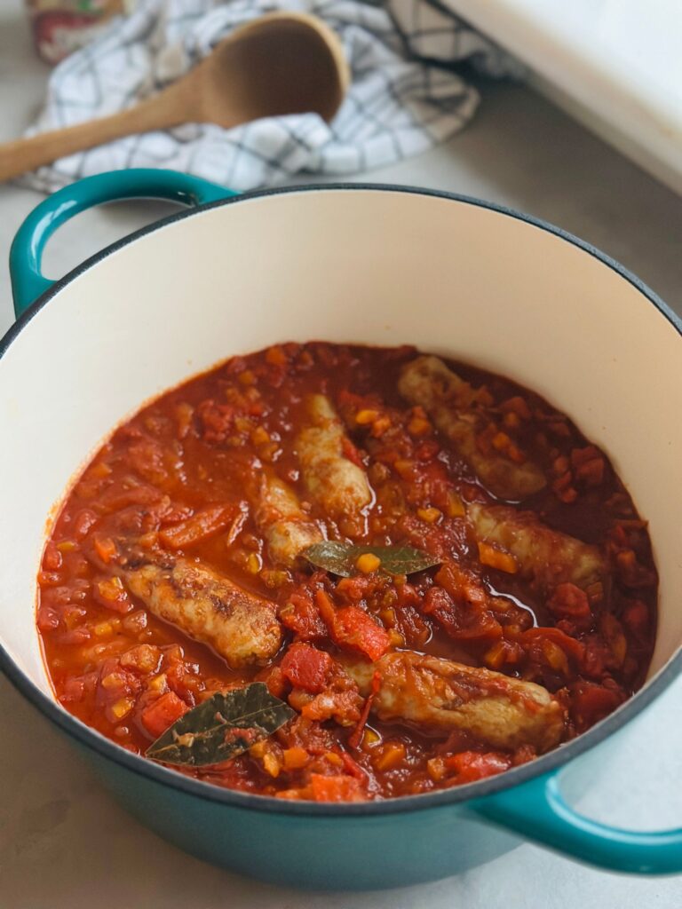 sausage casserole in a turquoise coloured Dutch oven